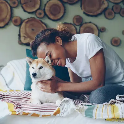 Una mujer abraza a su shiba inu en la cama